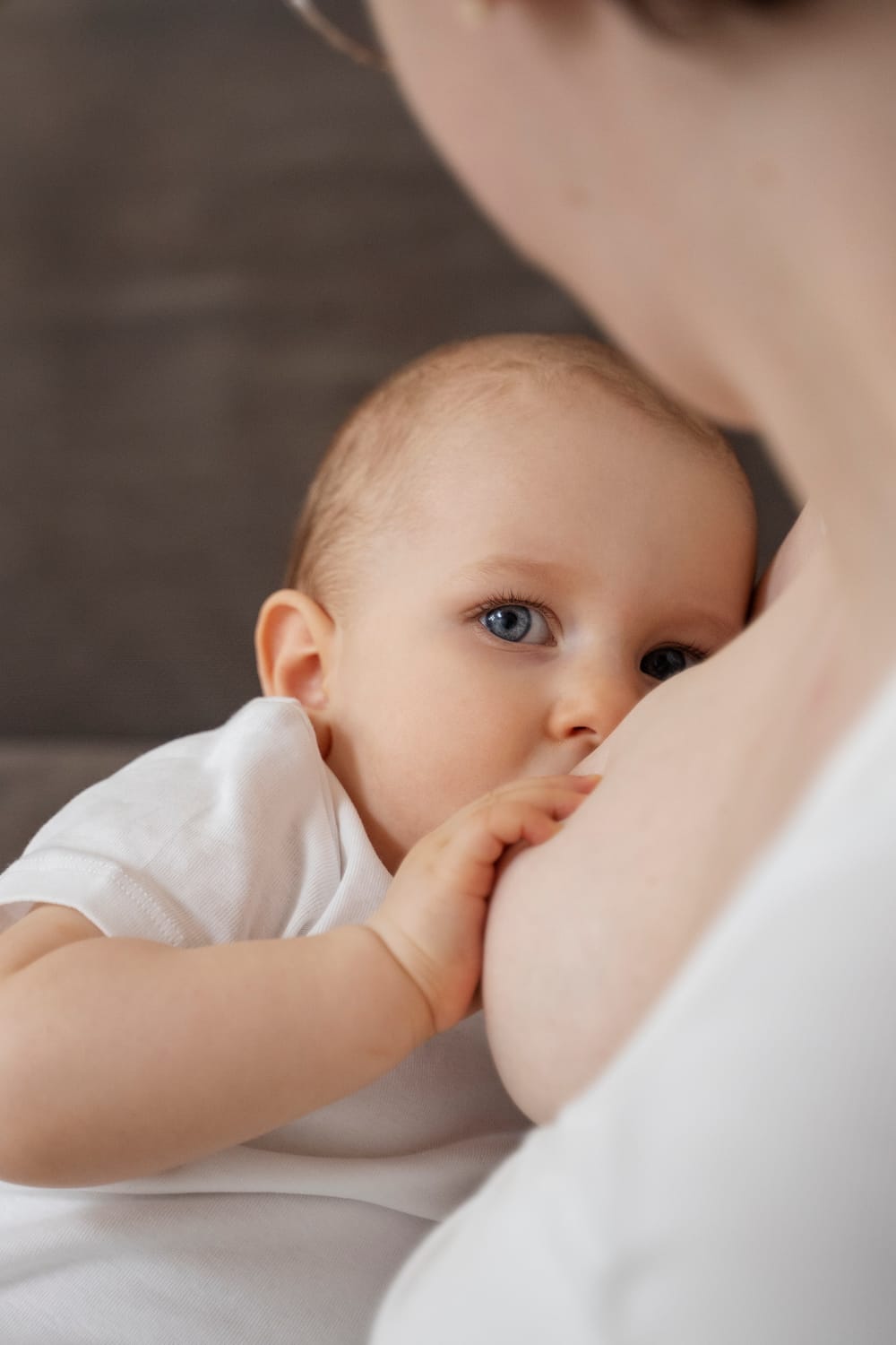 Bebé tomando pecho, en primer plano, mientras su madre lo sostiene con ternura